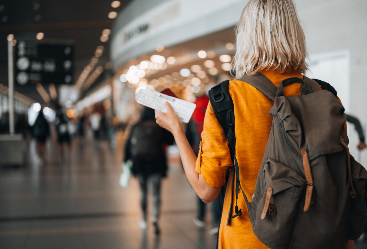 A woman at the airport holding a passport with a boarding pass.