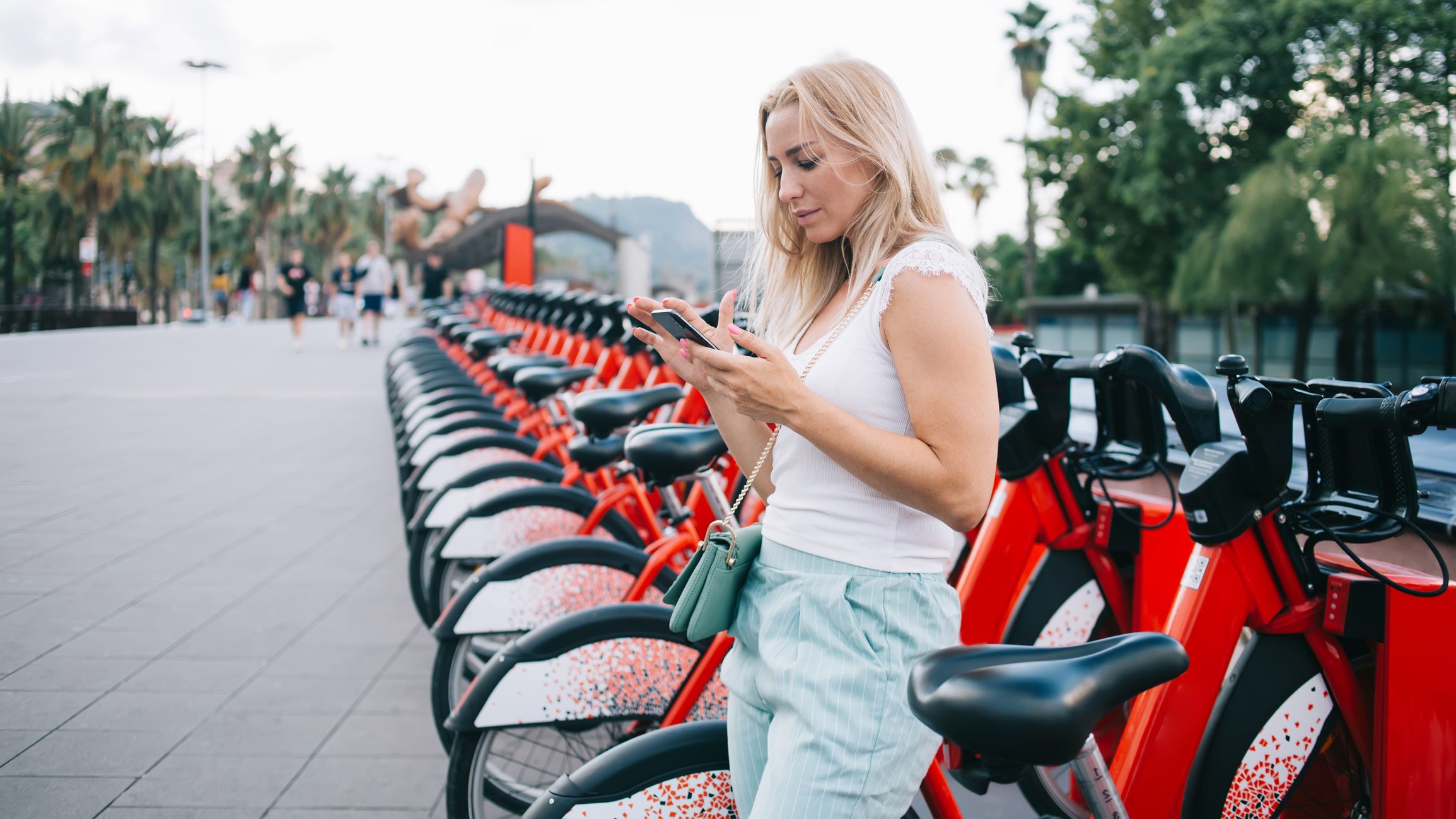 Tourist standing at urban station with electric bicycles for rent
