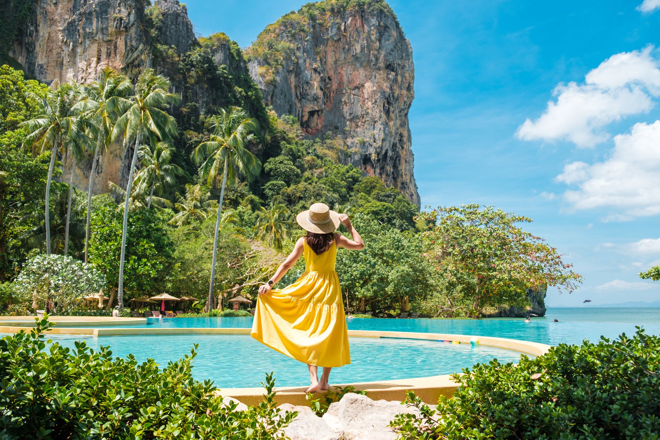 Woman tourist in yellow dress and hat traveling on Railay beach, Krabi, Thailand