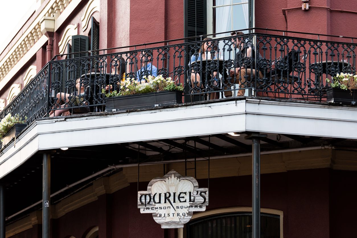 Old town Chartres street in Louisiana town, city, cast iron balcony building, people sitting in restaurant outdoor cafe Muriel's at Jackson Square