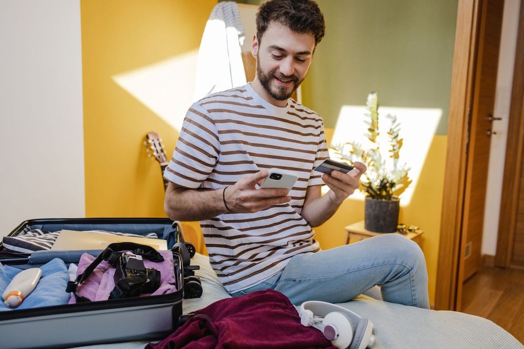 Young man buying tickets online and preparing for a trip