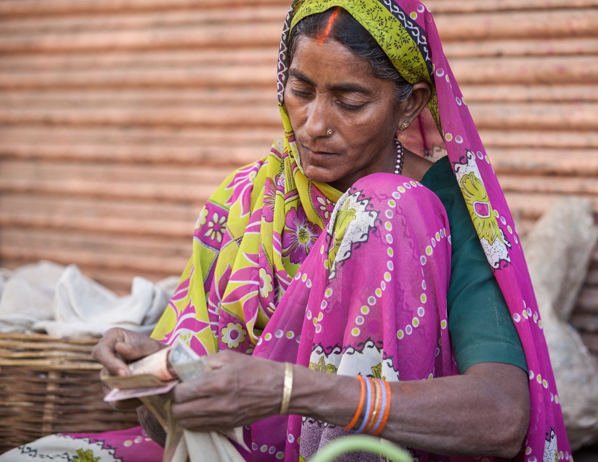Indian woman seller in farmers market counting money - Varanasi, India