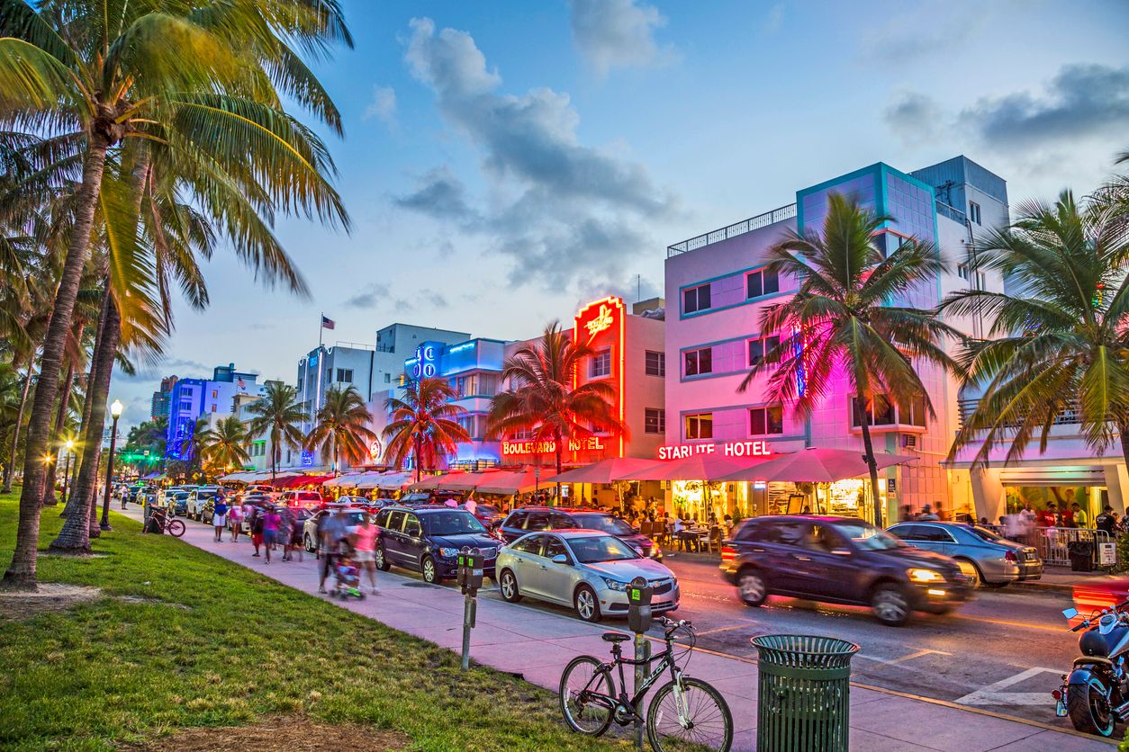 People enjoy palm trees and art deco hotels at Ocean Drive, Miami, Florida