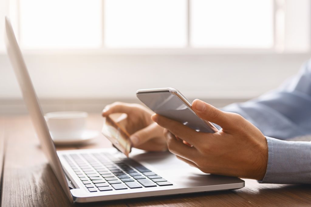 Unrecognizable businessman booking tickets online using smartphone and credit card