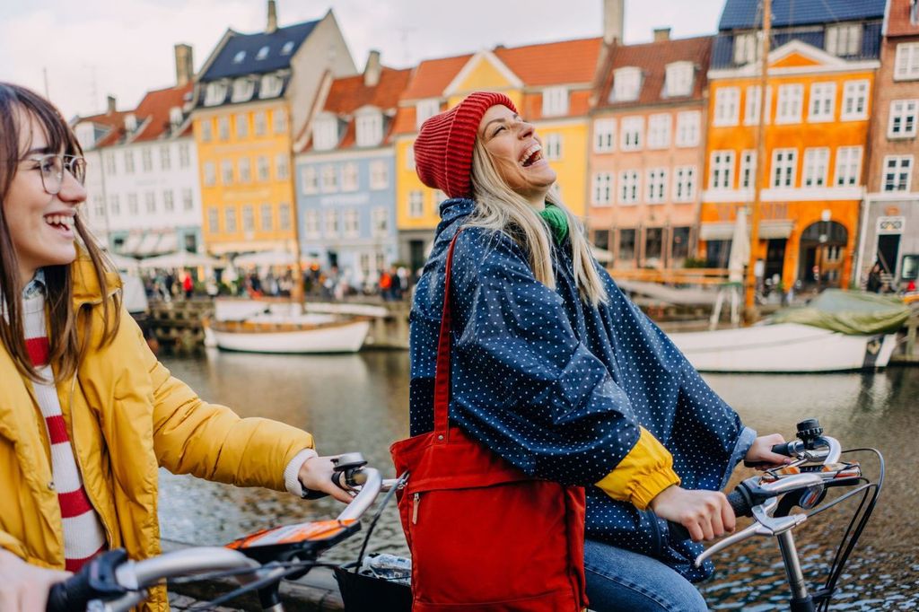 two young women riding bikes and having fun while discovering the new city