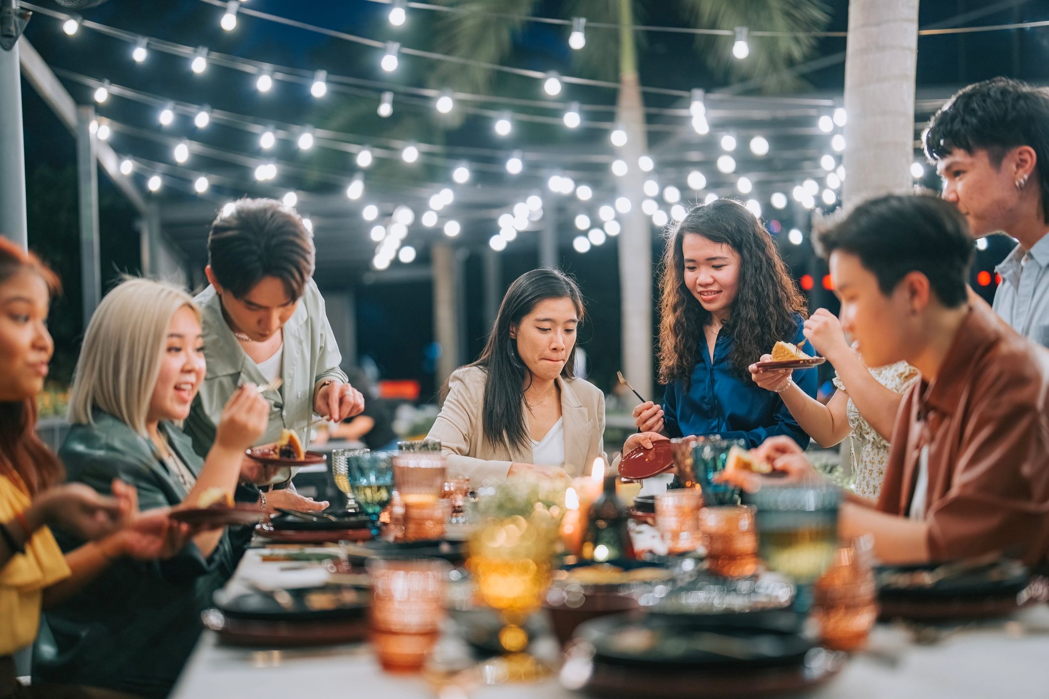 Group of people eating together in an outdoor setting having fun