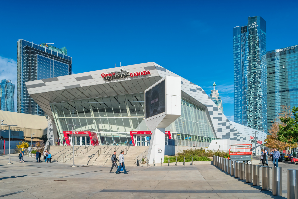 Pedestrians walk beside Ripley's Aquarium in downtown Toronto Ontario Canada on a sunny day.