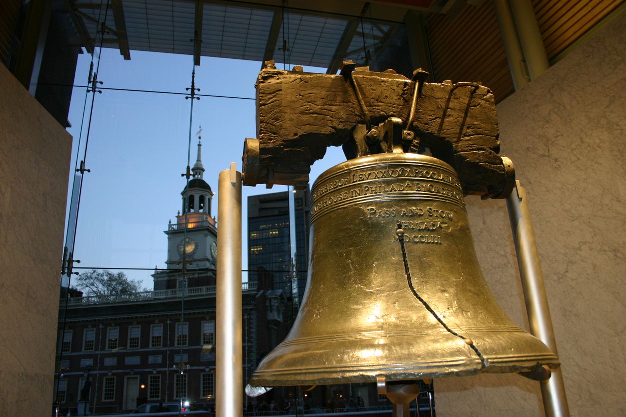 Close-up shot of the Liberty Bell with Independence Hall in the background at dusk