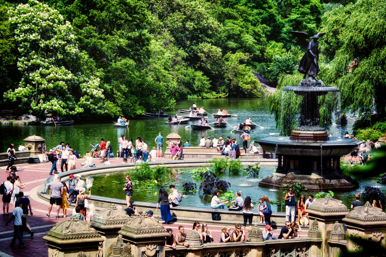 Central Park, Bethesda Fountain scene in Summer, Manhattan, New York City, USA with crowds of tourists and people on boats in the background