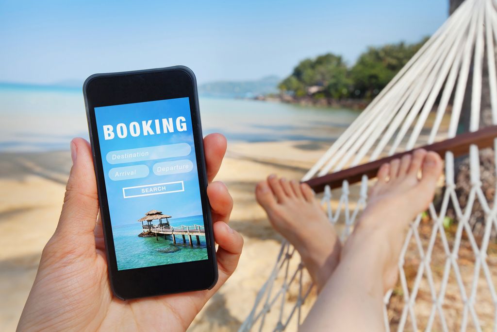 Travel booking, hotels and flights reservation on a phone from the beach.