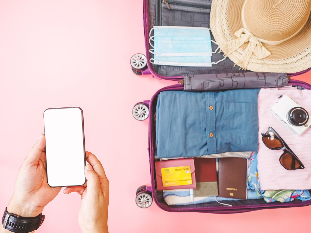 Booking online with packed suitcase ready to go.
