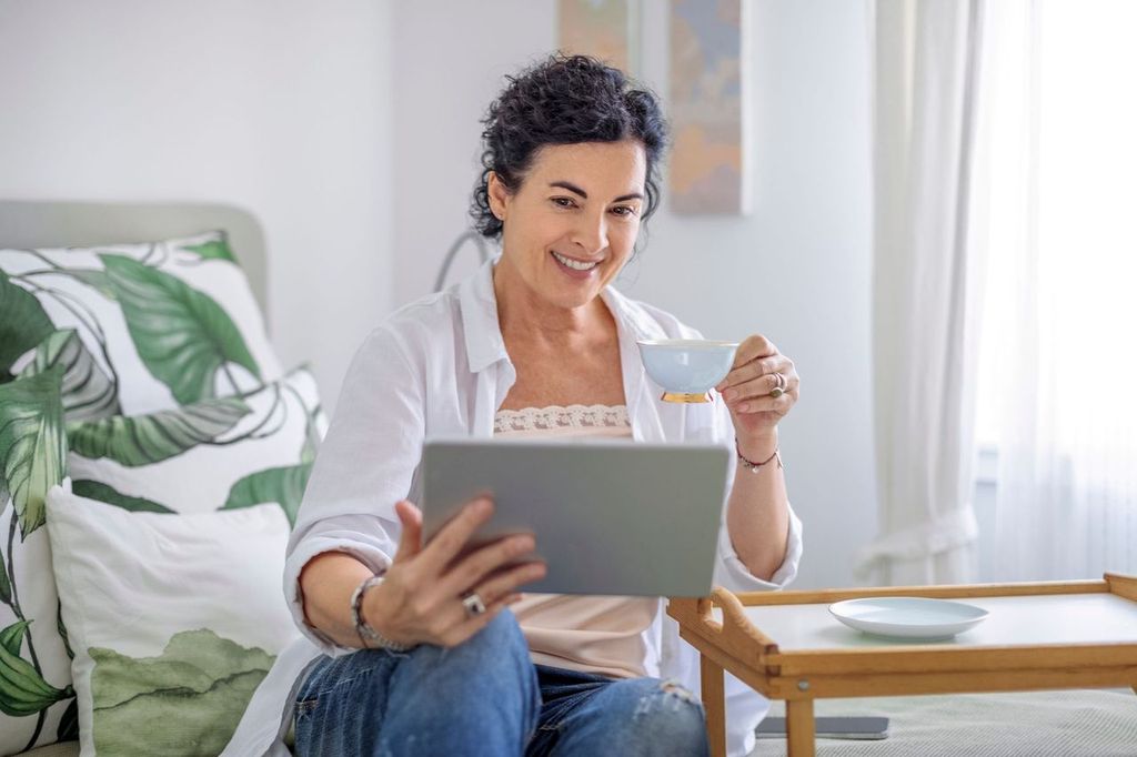 Woman booking a vacation from the comfort of her home while drinking coffee