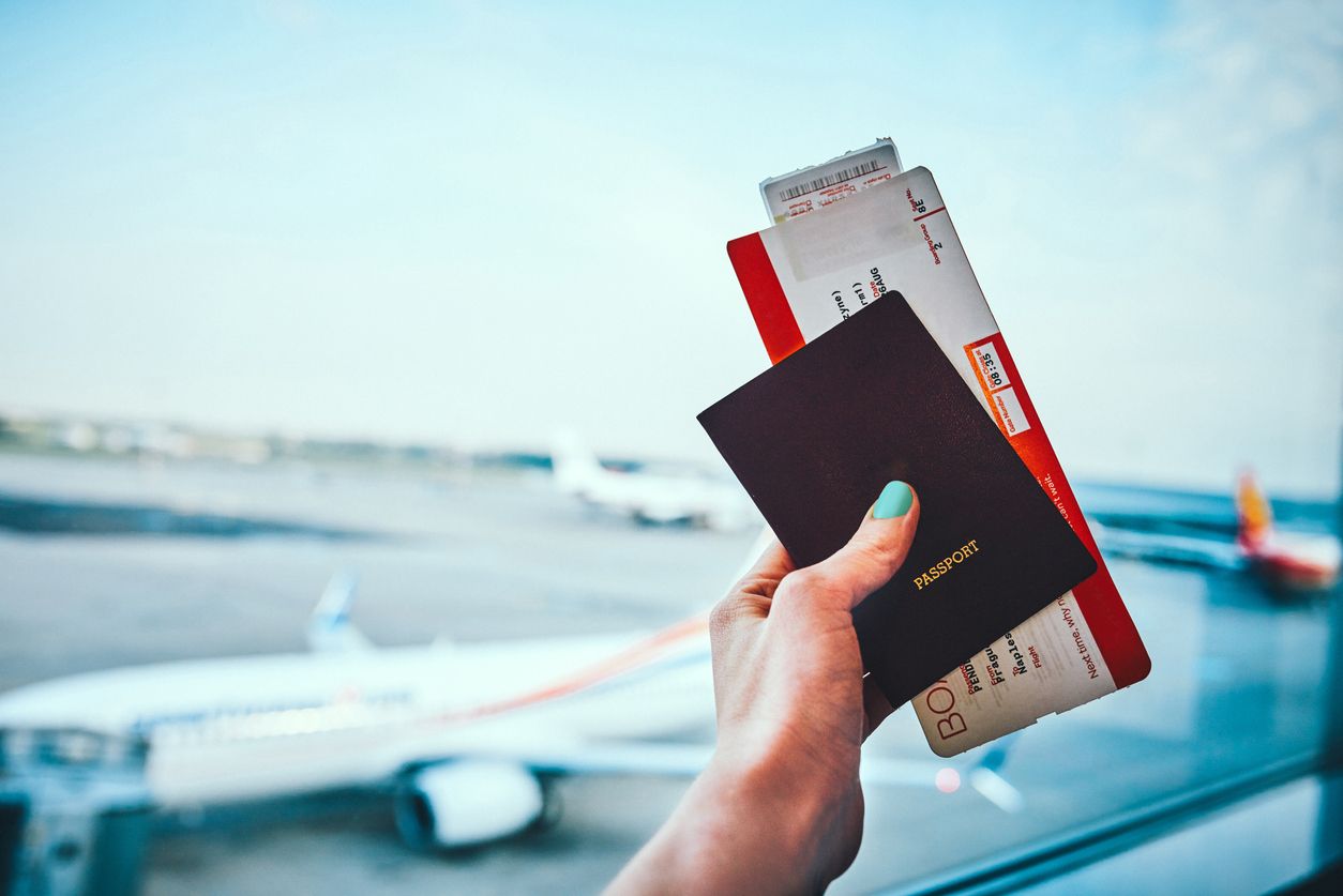woman holding up her passport and plane ticket before boarding her aircraft.