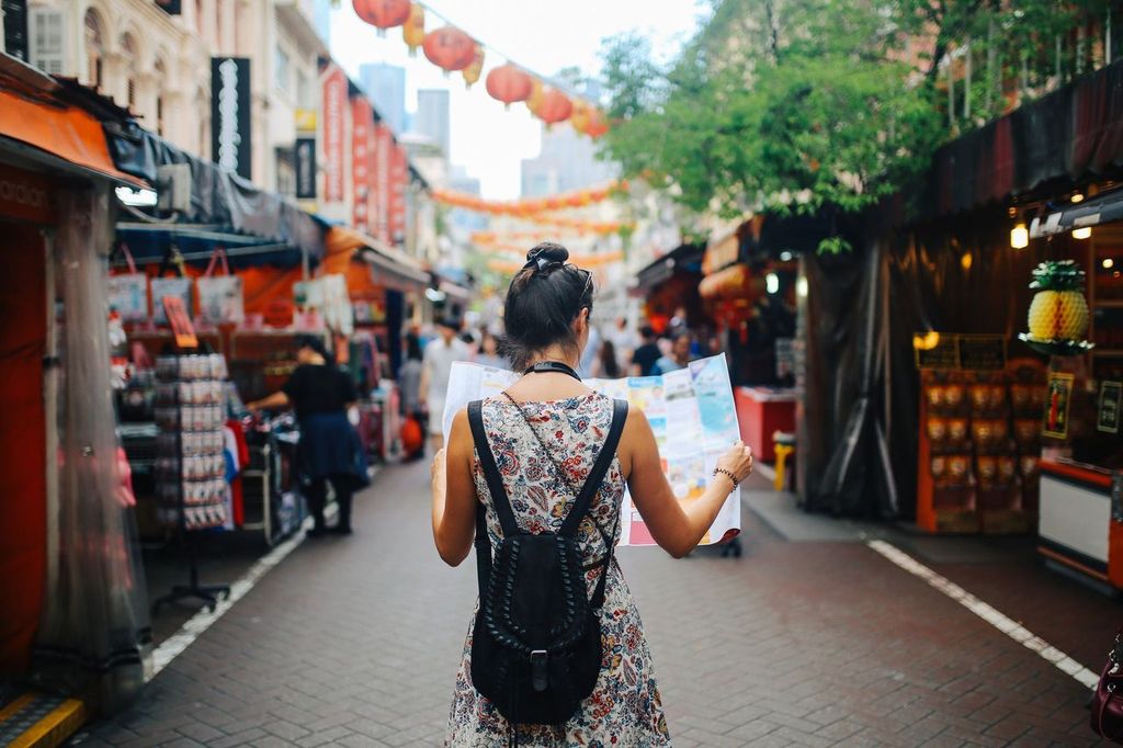 Young solo traveler woman in Singapore street market checking the map