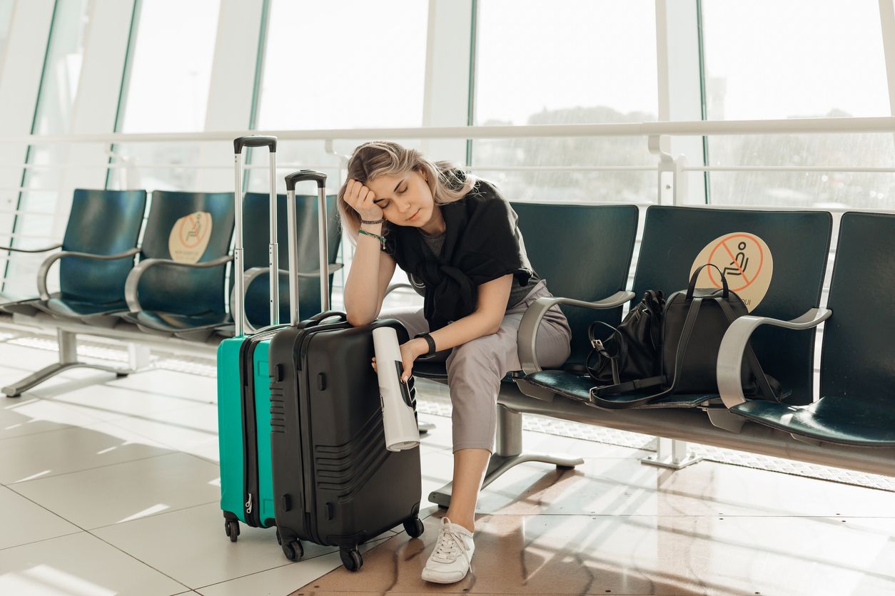 Bored blond woman with luggage, leaning elbow on bags