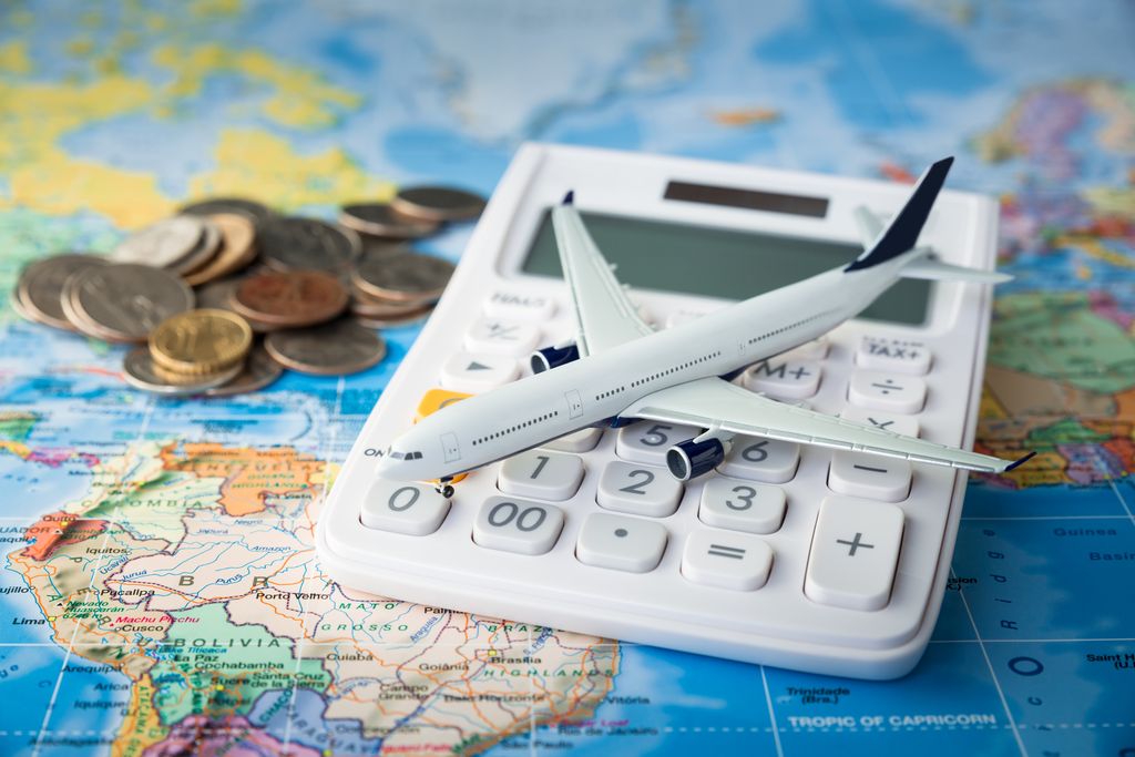 Travel budget concept with calculator, map, coins, and aircraft toy.