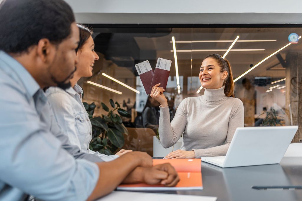 Couple sitting with manager at the travel agency office and reviewing contract