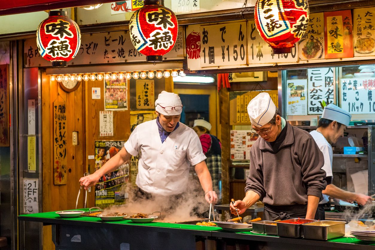 Men cook traditional Japanese street food in Osaka, Japan.