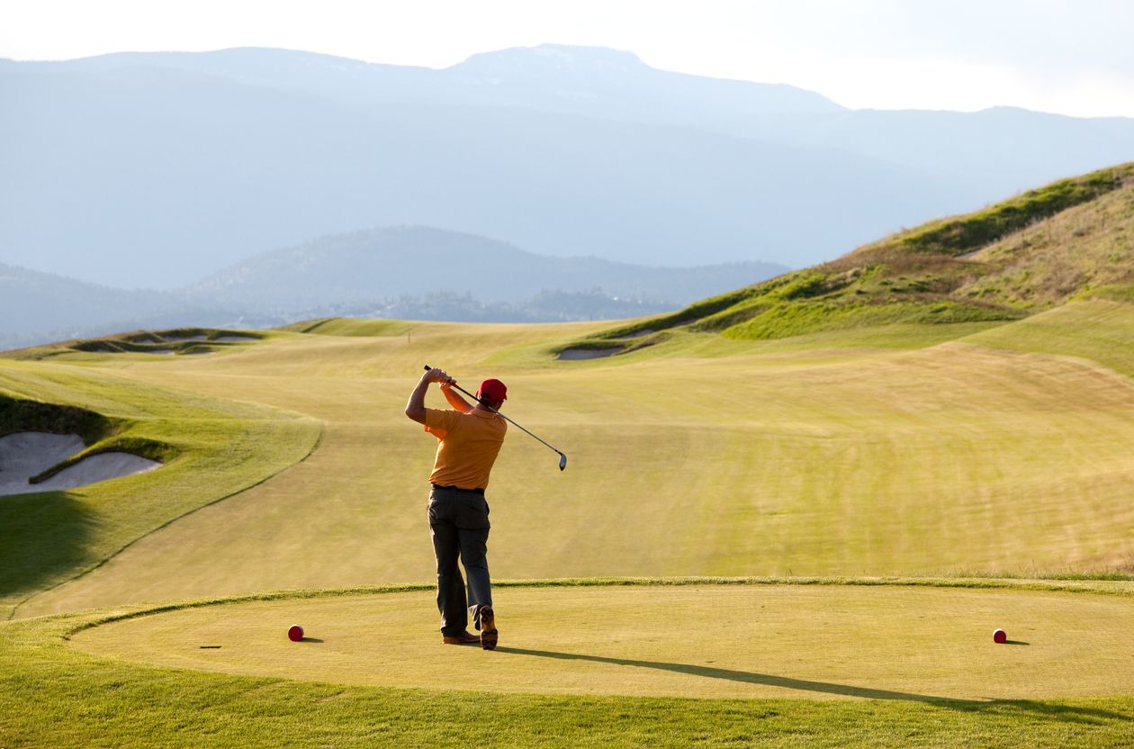 A golfer teeing off on a dramatic golf course in the mountains. Kelowna, British Columbia