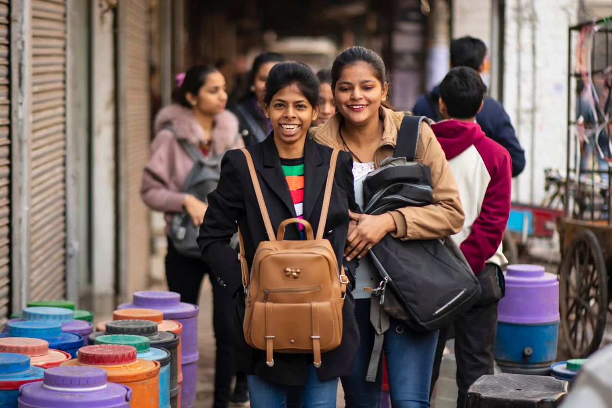 Young women carry backpacks on a chest at a street of Old Delhi, India to avoid pickpocketing