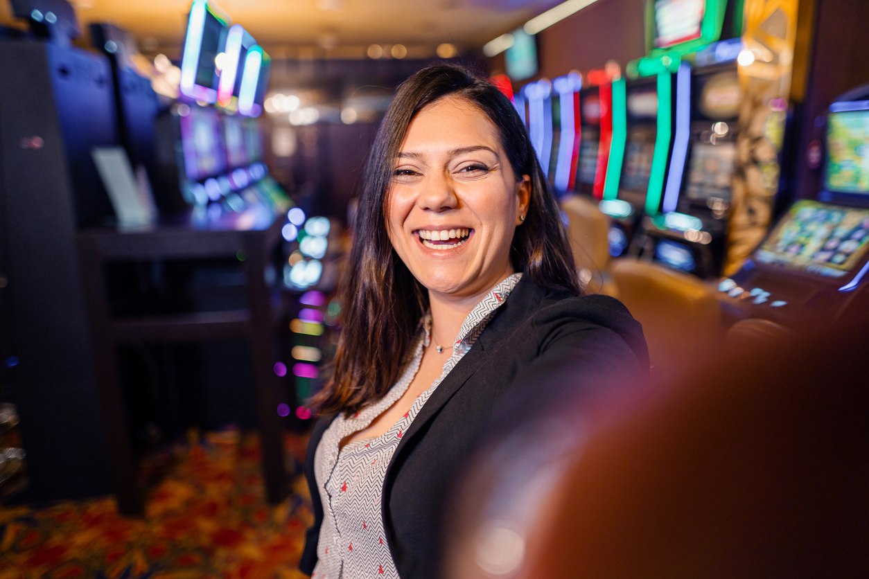 Portrait of a happy female casino player near slot machines