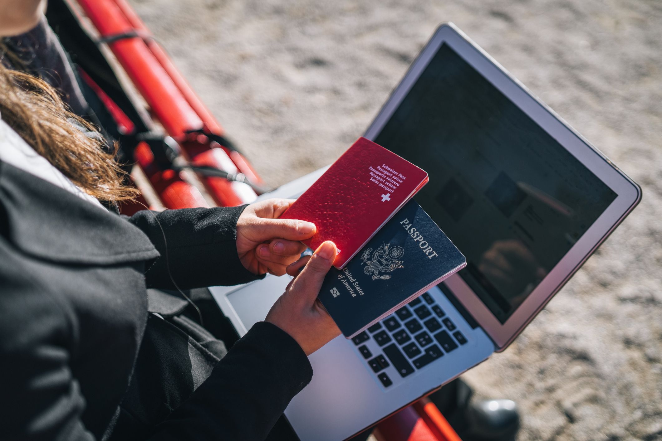 Businesswoman booking trip on laptop while holding two passports