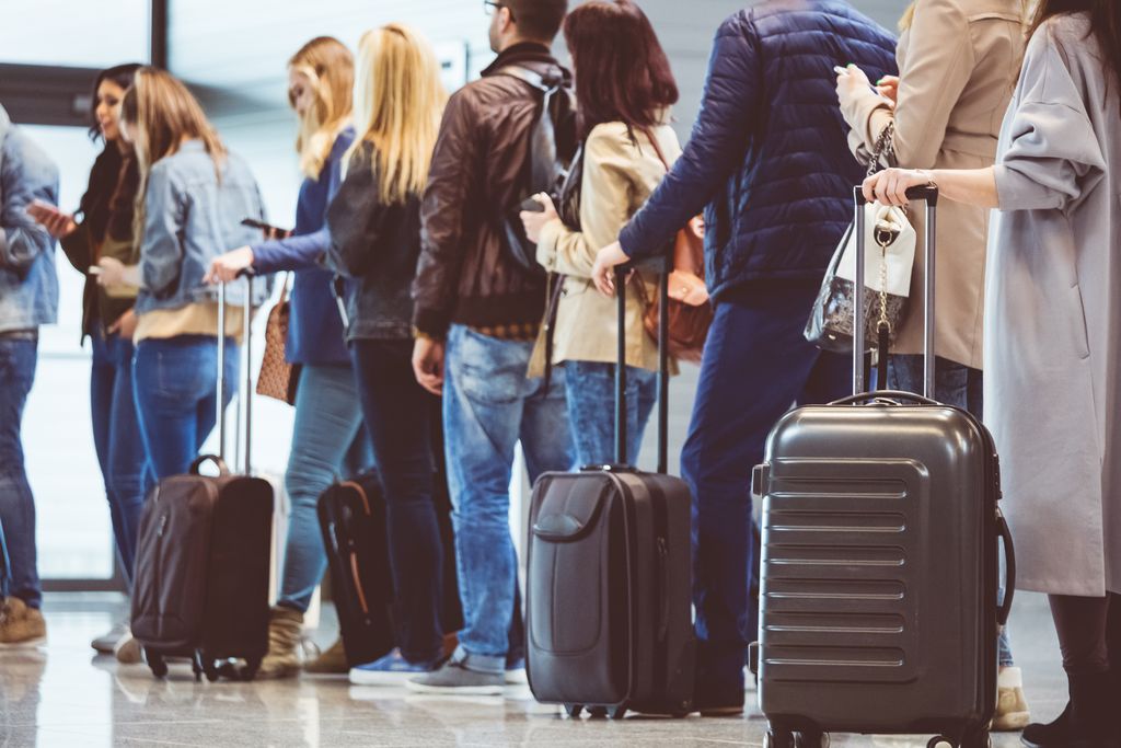 Group of people standing in queue at boarding gate with luggage.