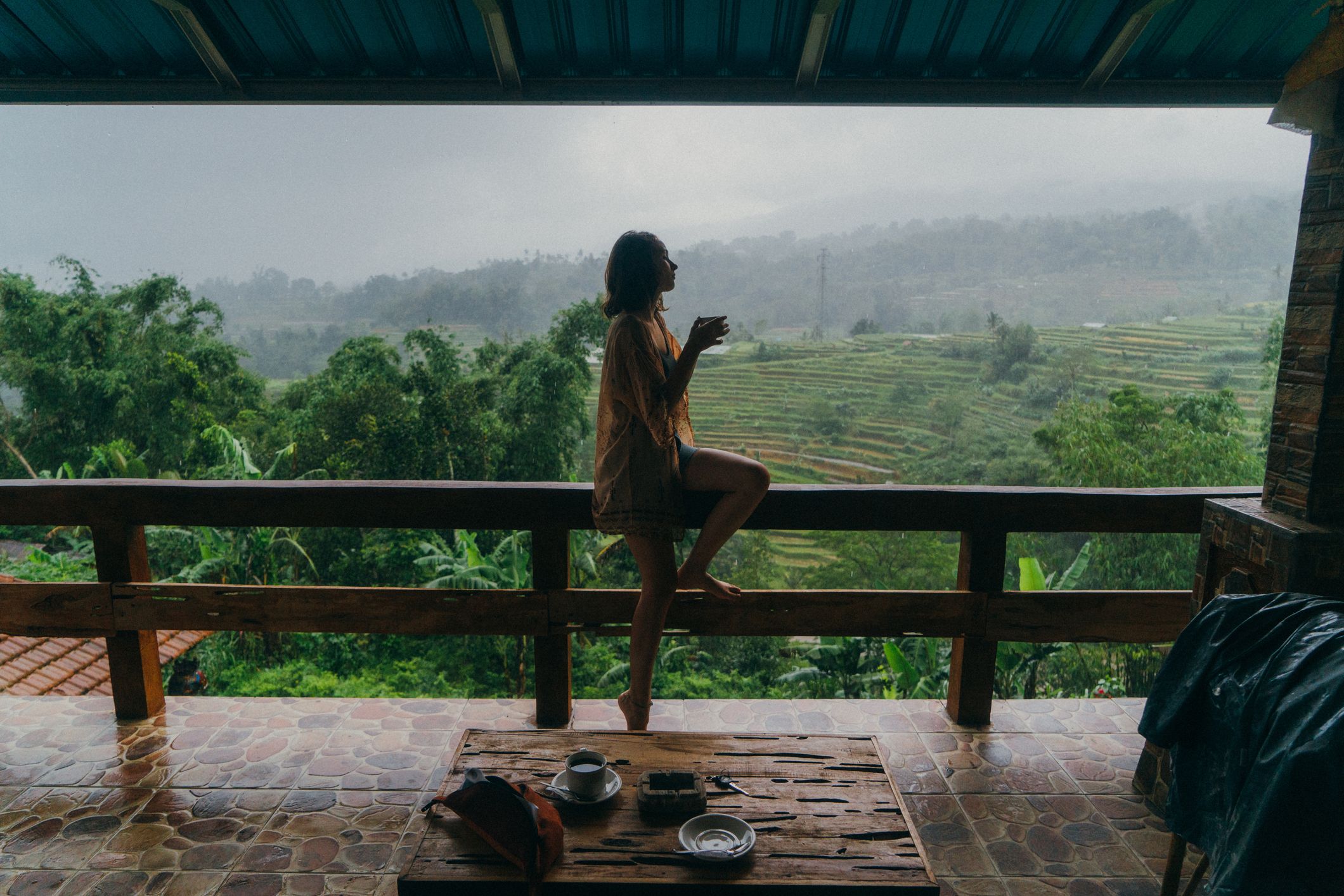 Woman drinking tea on balcony with view on rice fields in Bali, Indonesia