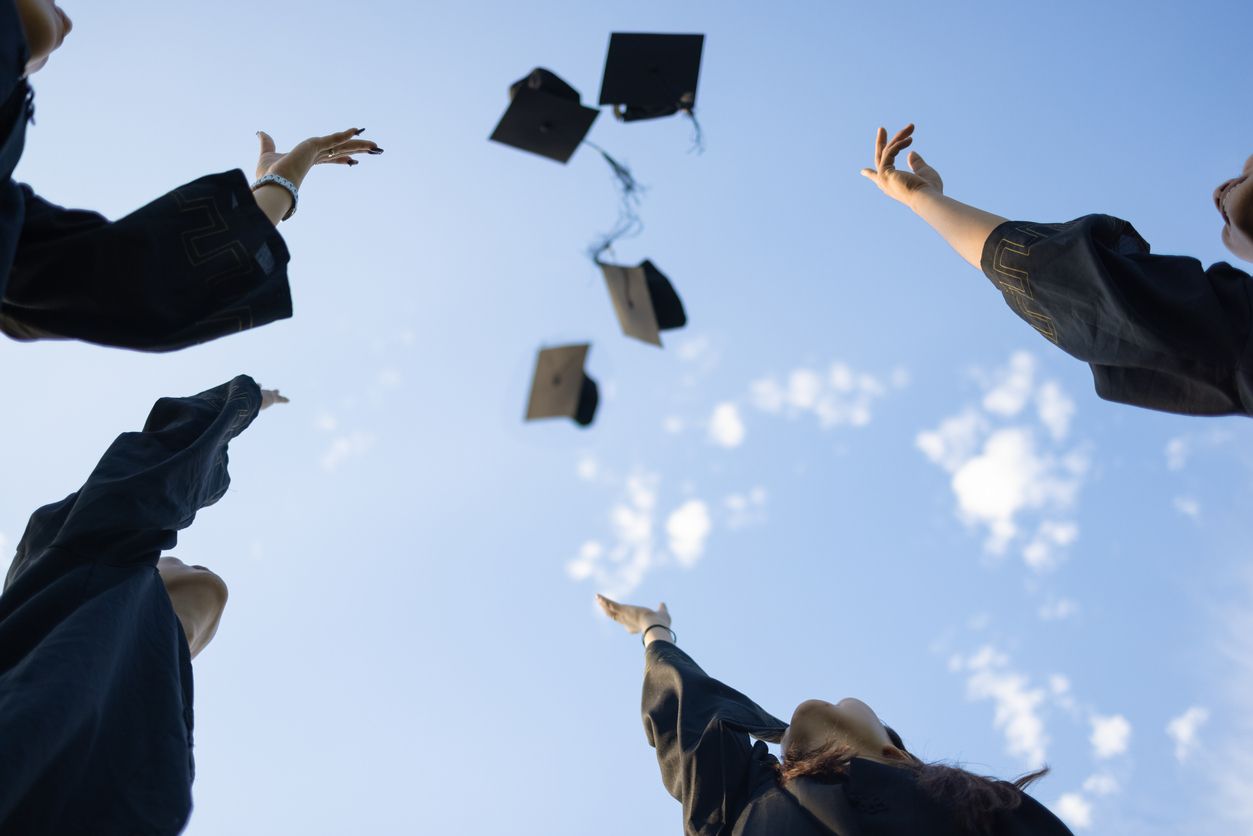 A group of graduates throwing their caps in the air in celebration