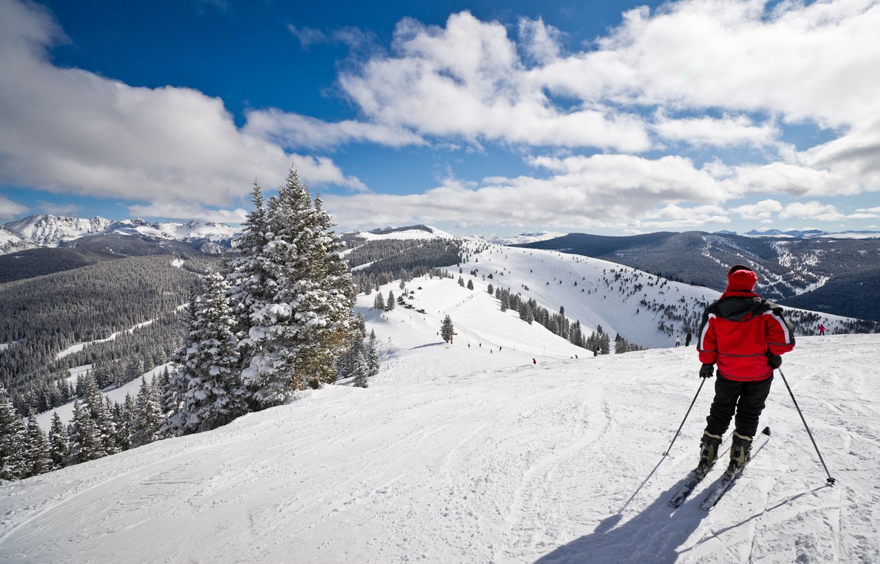 Female skier standing with Rocky Mountains in the background in Vail, Colorado