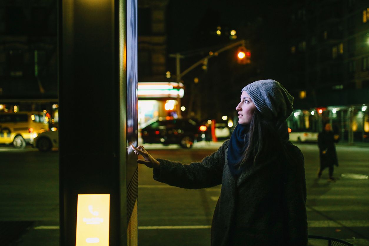 Young woman using interactive touch screen city display to check for information, New York City, USA.