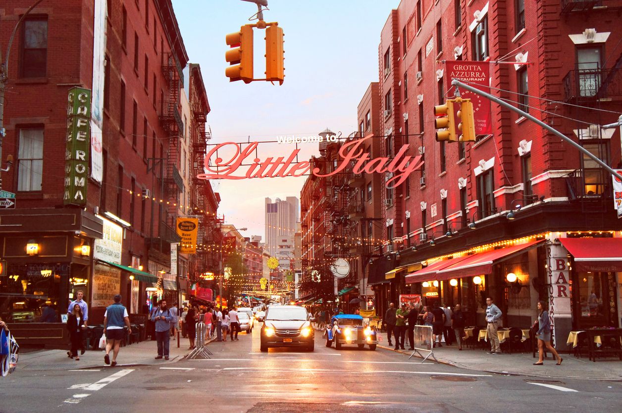 People and cars move alongside the Little Italy Mulberry street by evening in the New York City