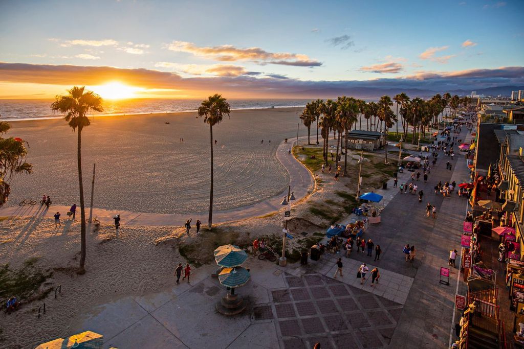 Tourists walking on footpath by beach during sunset in Venice, California, USA