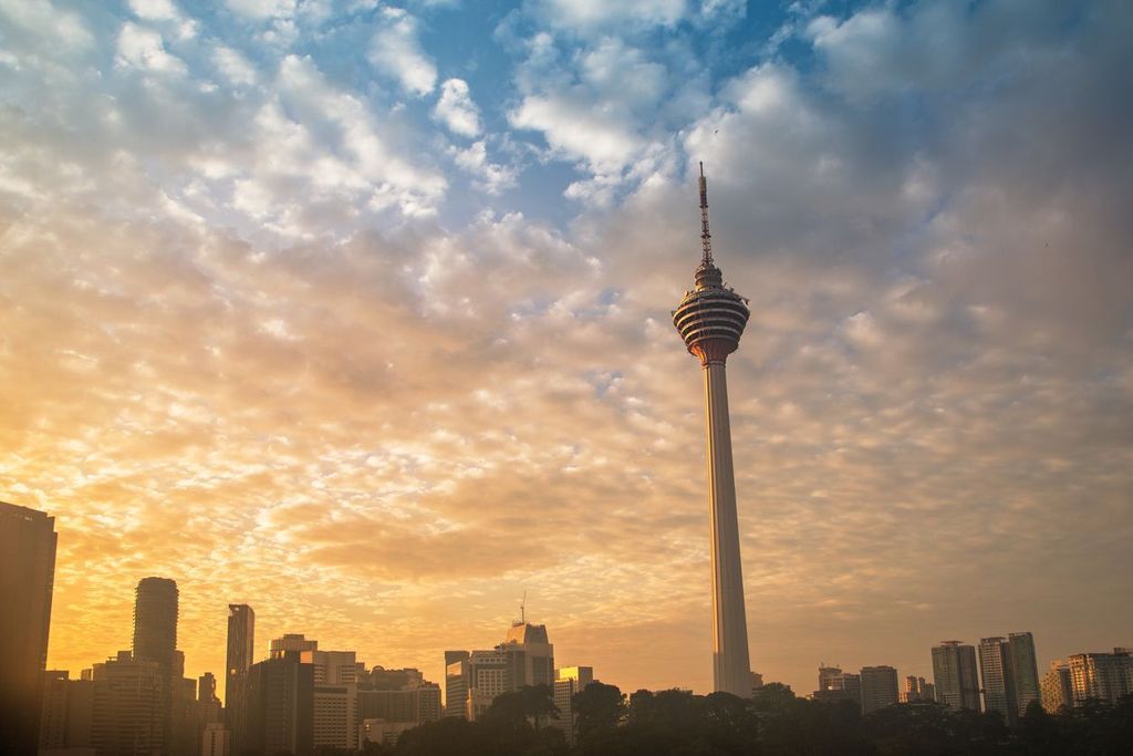 Misty sunrise over city skyline with Menara Kuala Lumpur Tower