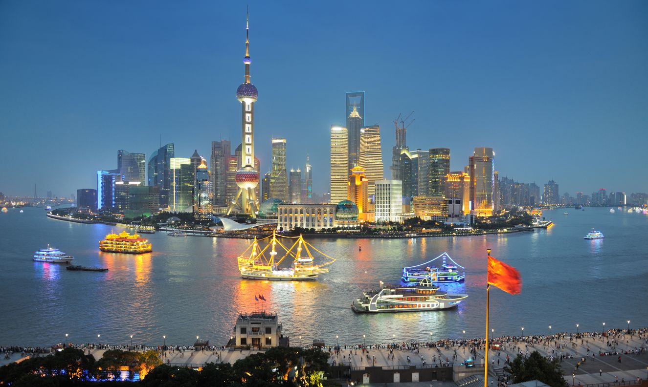 Oriental Pearl Tower and Shanghai Skyline with the Bund, the famous pedestrian walk in front and boat tours in the center