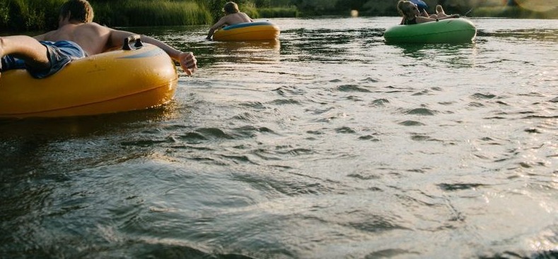 Young people floating down river in inner tubes