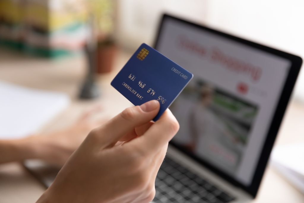 Close up woman holding plastic credit card and using laptop for online shopping.