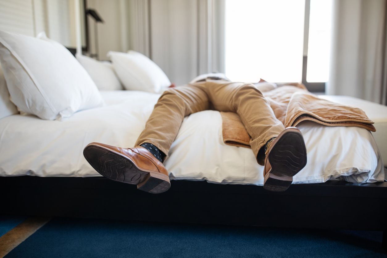 Businessman lying on hotel bed.