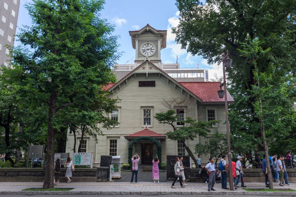 Tourists admiring the Sapporo Clock Tower in Hokkaido, Japan