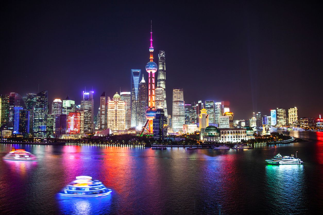 Shanghai's Pudong District's skyscrapers at night with dinner river cruise party boats