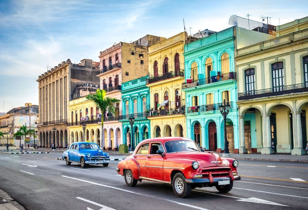 two vintage taxi cars in front of historic buildings in Old Havana, Cuba