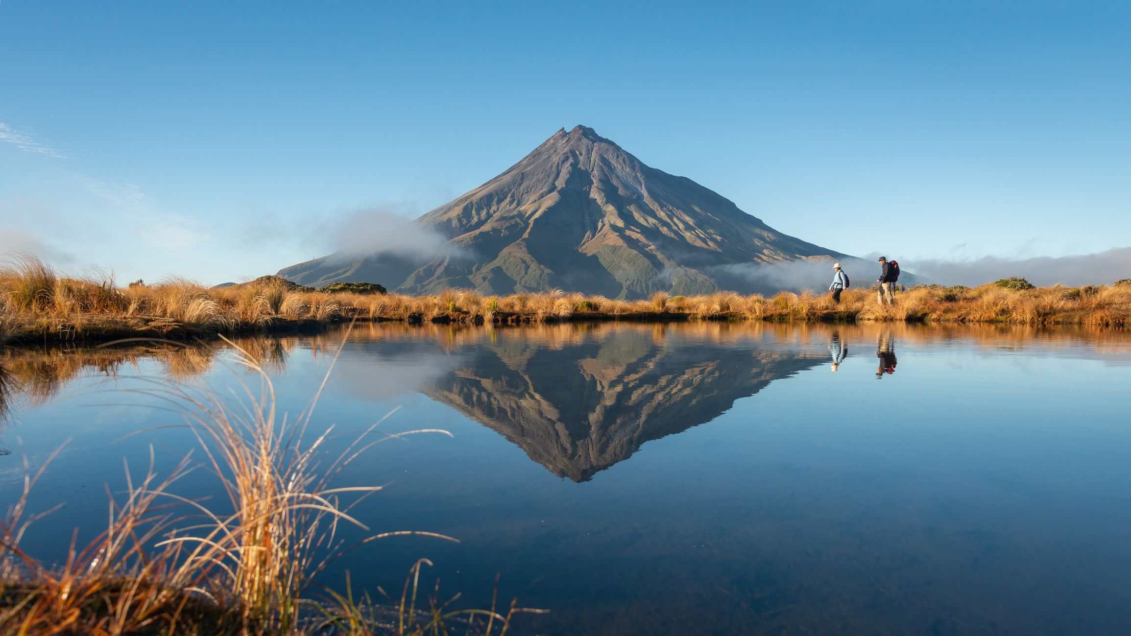 Two people hiking Pouakai circuit with Mount Taranaki in focus