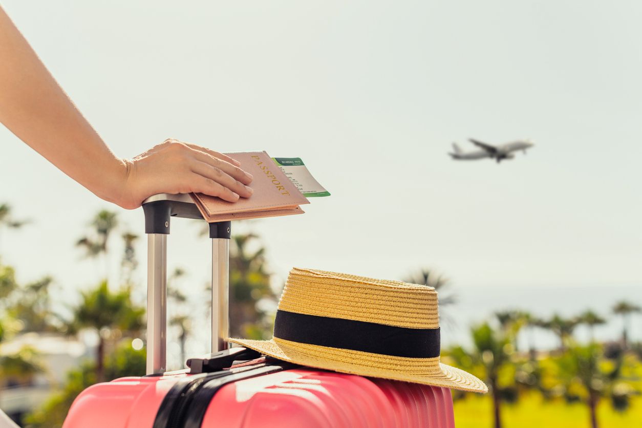 Woman with pink suitcase and passport with boarding pass.