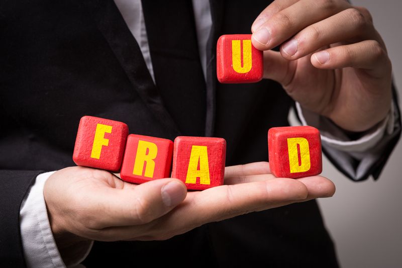 Fraud concept with a businessman holding blocks spelling it out
