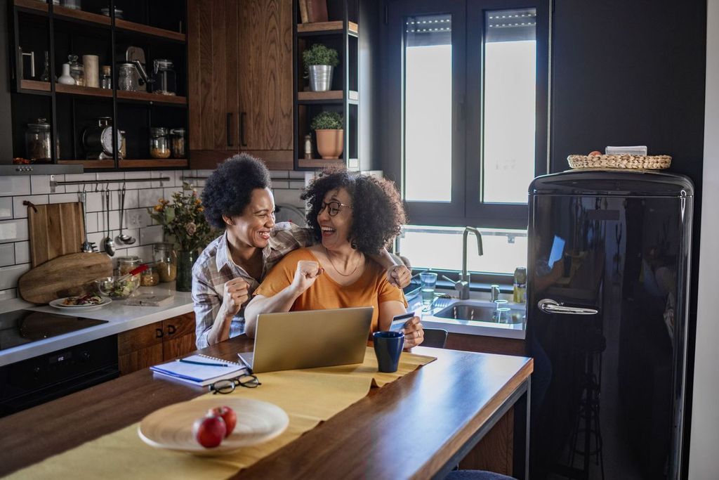 Two women booking online airline tickets for their next trip via laptop from home