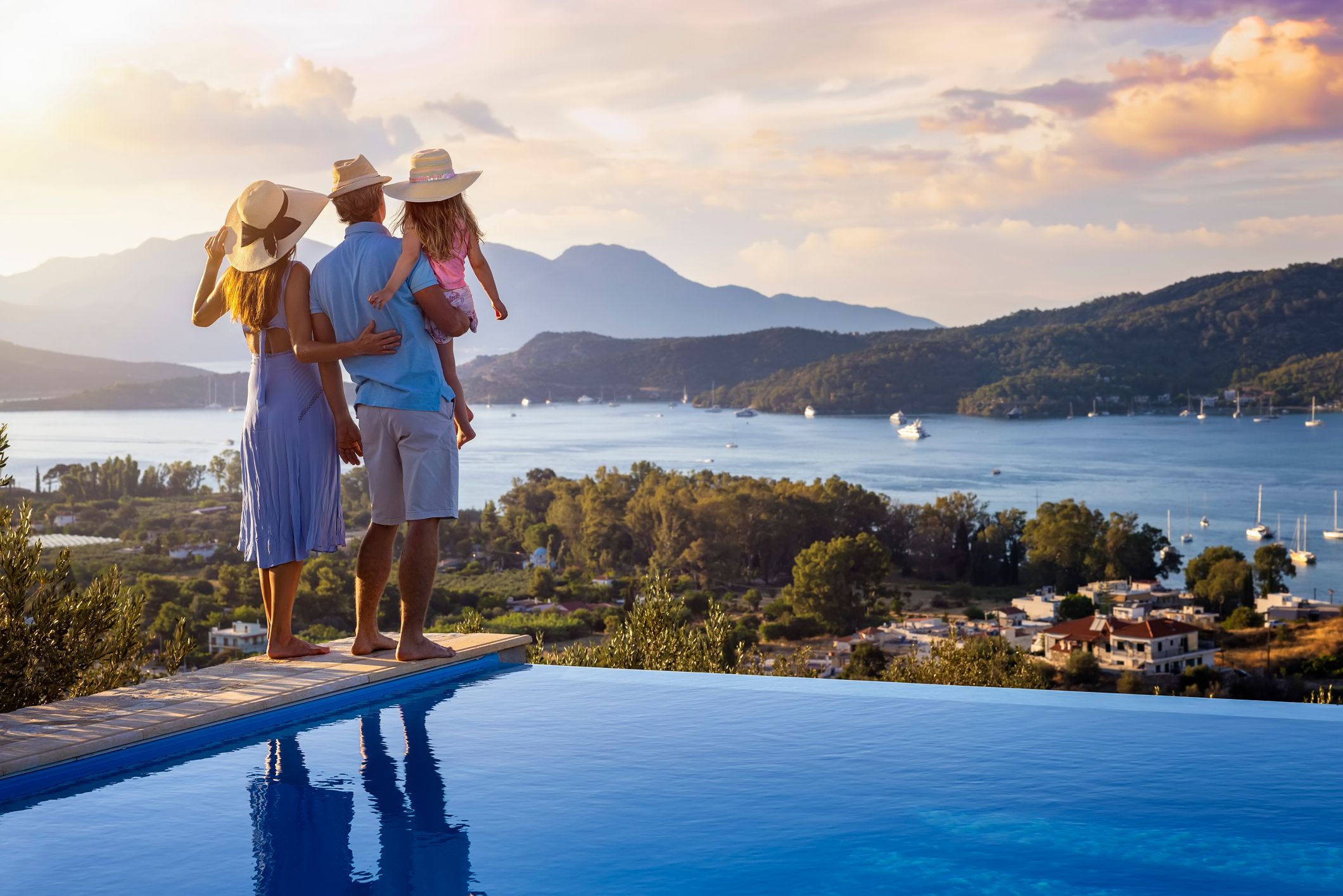 A family on summer holidays stands by the swimming pool