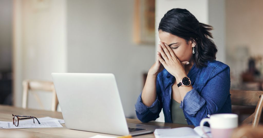 young woman looking stressed while using a laptop