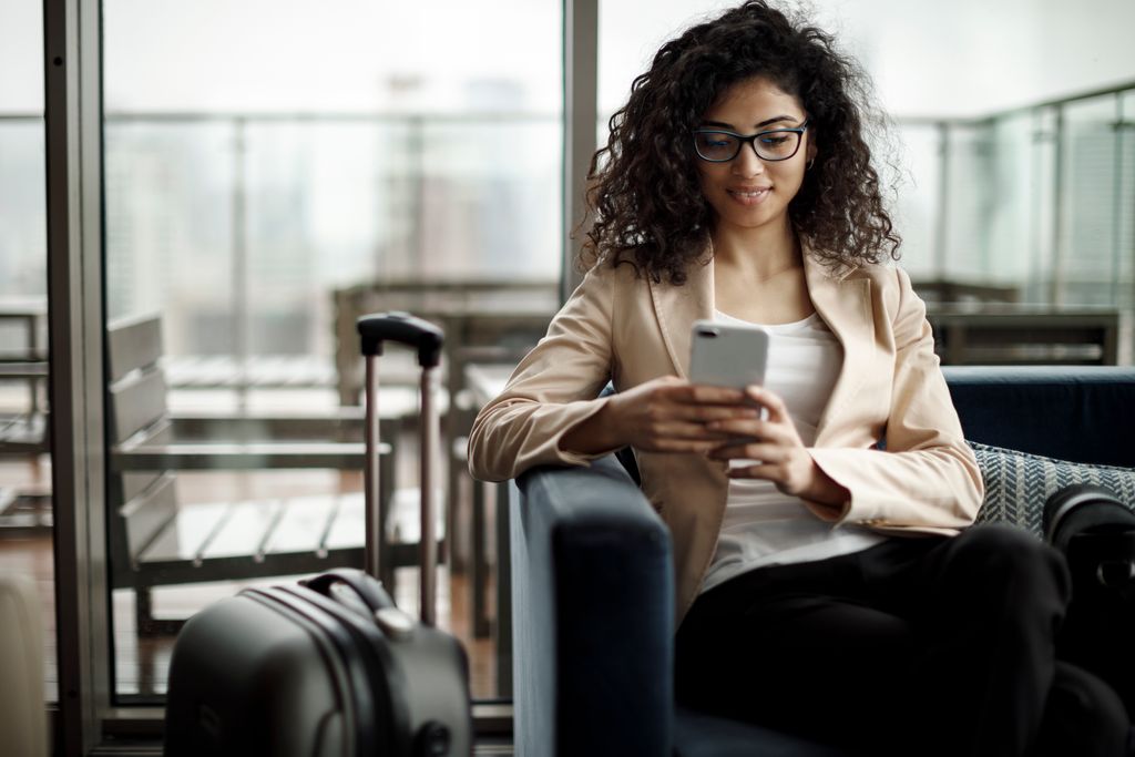 Young businesswoman using mobile phone with luggage.