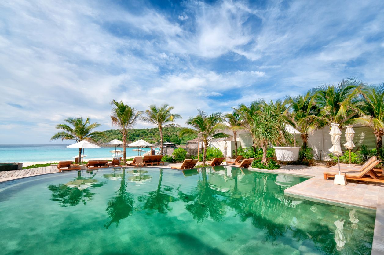 Tropical Luxury Resort pool with palm trees and ocean in the background, Phuket, Thailand.