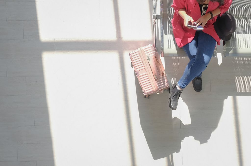 Woman on mobile phone at the airport with suitcase